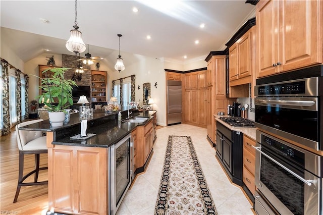 kitchen with hanging light fixtures, beverage cooler, a large island with sink, appliances with stainless steel finishes, and dark stone counters