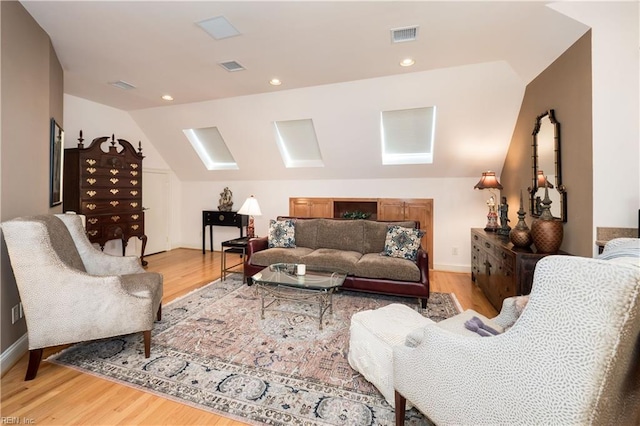 living room with lofted ceiling with skylight and light hardwood / wood-style flooring