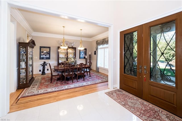 foyer entrance with french doors, light hardwood / wood-style flooring, and crown molding