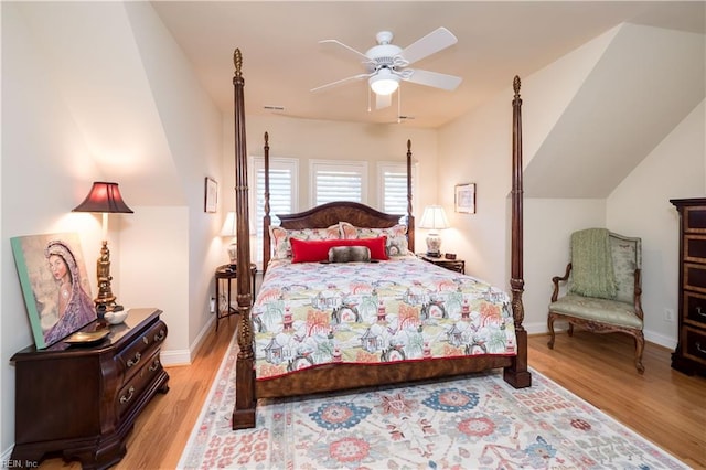 bedroom with ceiling fan, vaulted ceiling, and light hardwood / wood-style flooring