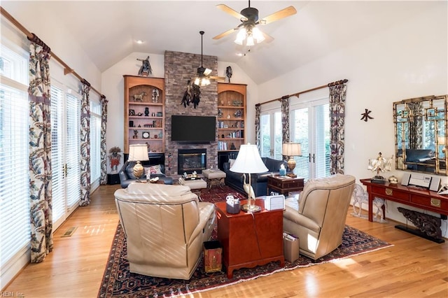 living room featuring built in features, ceiling fan, light wood-type flooring, and a wealth of natural light