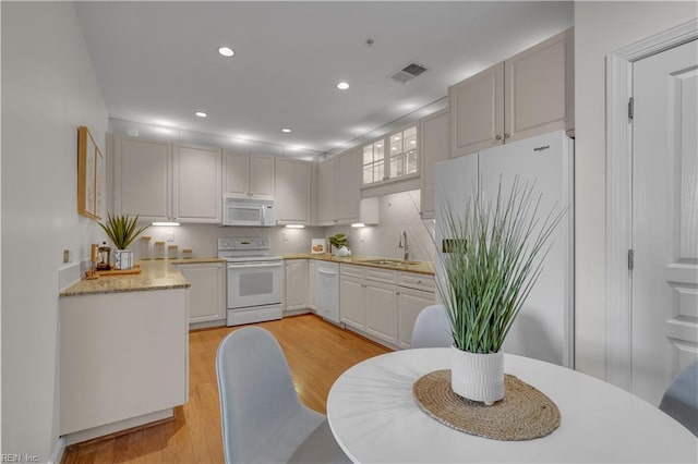 kitchen featuring white cabinetry, sink, light wood-type flooring, and white appliances