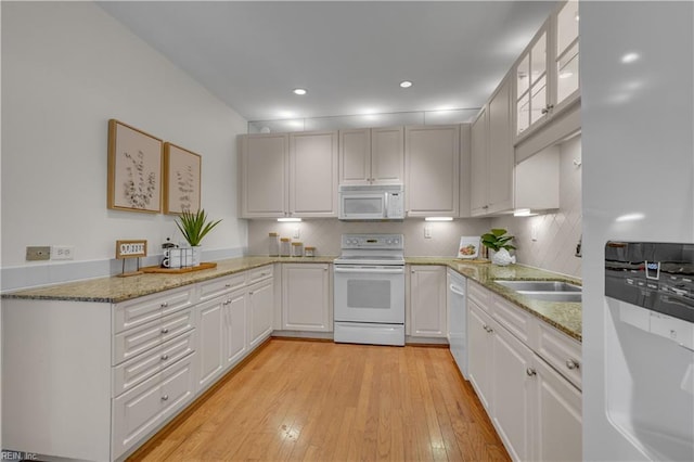 kitchen featuring sink, light wood-type flooring, white cabinetry, light stone counters, and white appliances