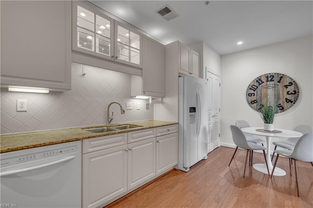 kitchen with sink, light wood-type flooring, white cabinetry, white appliances, and tasteful backsplash