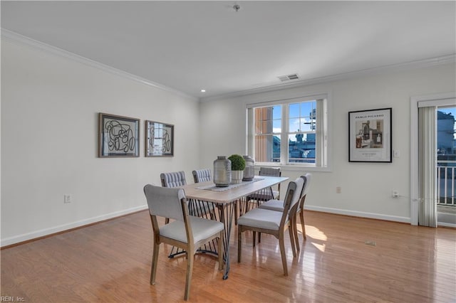 dining area with ornamental molding and light hardwood / wood-style flooring