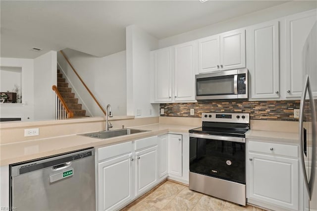 kitchen featuring appliances with stainless steel finishes, kitchen peninsula, sink, white cabinetry, and backsplash