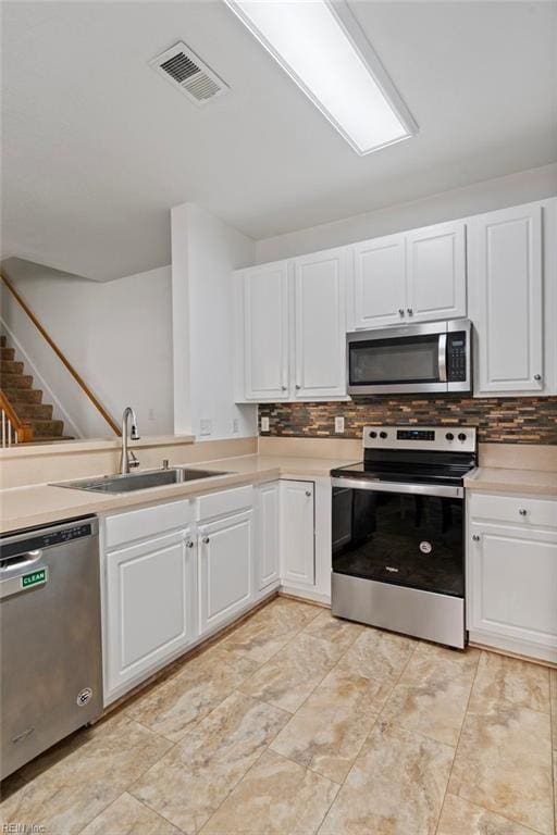 kitchen with stainless steel appliances, white cabinetry, and sink