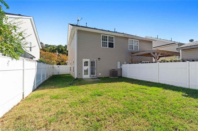 back of property with central AC and a lawn