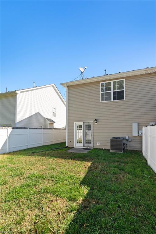 rear view of property featuring central AC unit and a yard