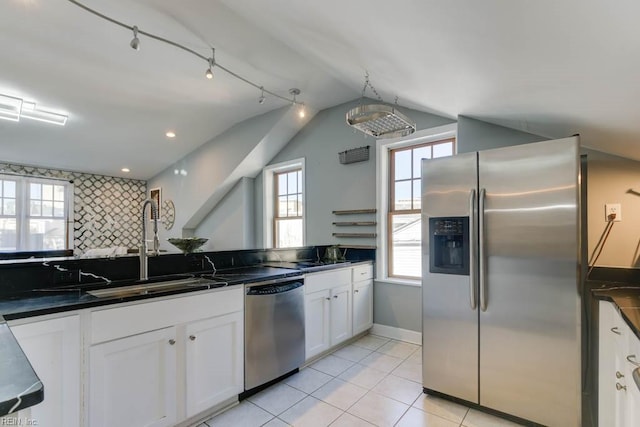 kitchen with lofted ceiling, white cabinets, backsplash, appliances with stainless steel finishes, and sink