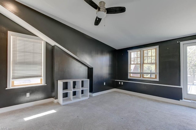 unfurnished living room featuring lofted ceiling, light carpet, a healthy amount of sunlight, and ceiling fan