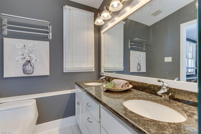 bathroom with toilet, vanity, and tile patterned flooring