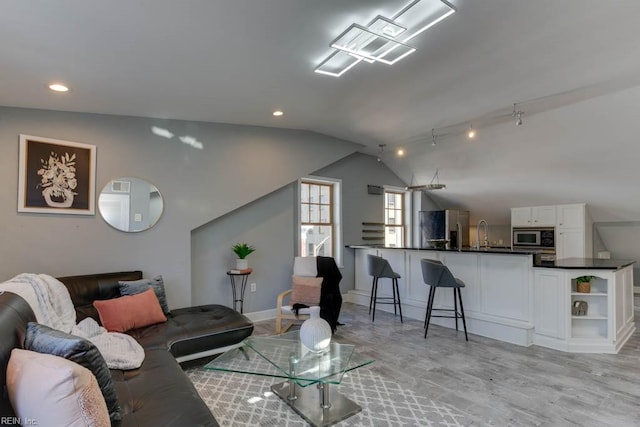 living room with lofted ceiling, sink, and light wood-type flooring