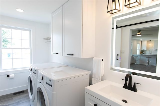 clothes washing area featuring cabinets, sink, light hardwood / wood-style flooring, ceiling fan, and separate washer and dryer