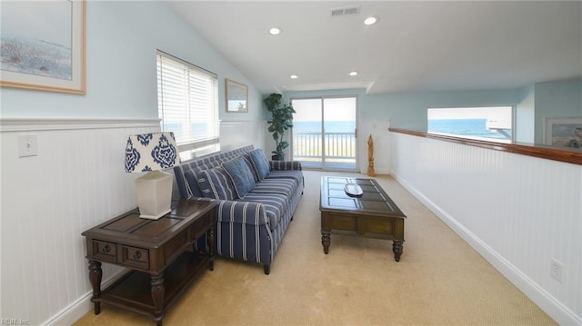 interior space featuring lofted ceiling, a healthy amount of sunlight, light colored carpet, and a water view