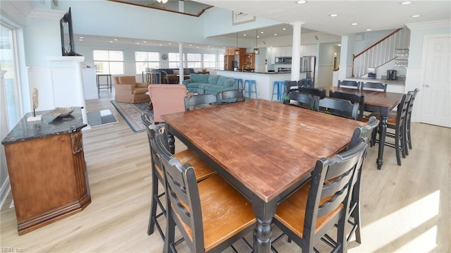 dining space with light hardwood / wood-style floors, crown molding, and decorative columns