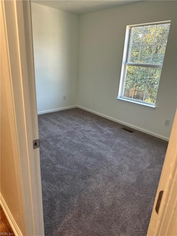 spare room with dark colored carpet