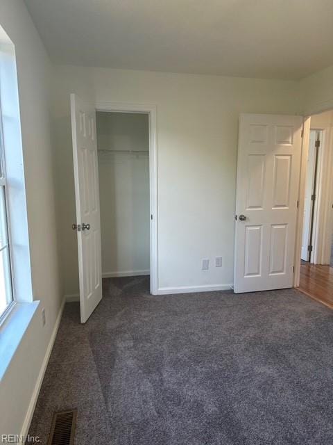 unfurnished bedroom featuring dark carpet and a closet