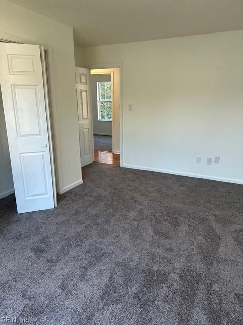 spare room with dark carpet