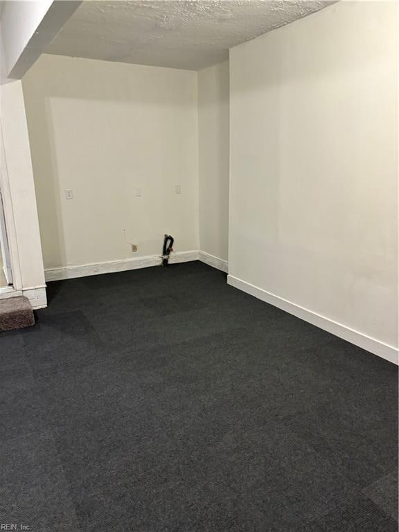 empty room with a textured ceiling and dark carpet