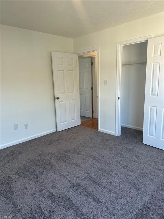 unfurnished bedroom featuring a closet and dark carpet