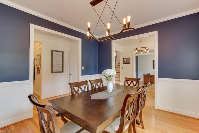 dining room with light hardwood / wood-style floors, crown molding, and a chandelier