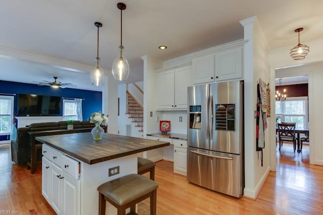 kitchen featuring stainless steel fridge, a center island, white cabinetry, and wood counters