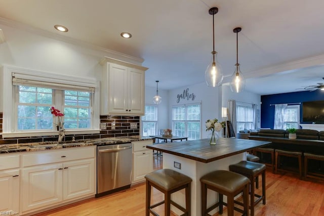 kitchen featuring stainless steel dishwasher, a breakfast bar area, a wealth of natural light, and tasteful backsplash