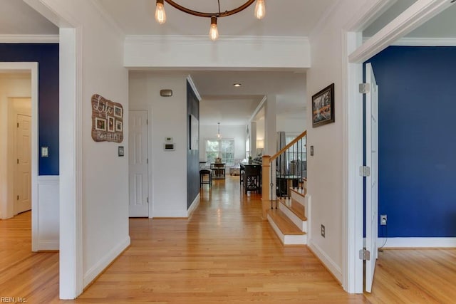 hallway with light hardwood / wood-style floors, a notable chandelier, and ornamental molding