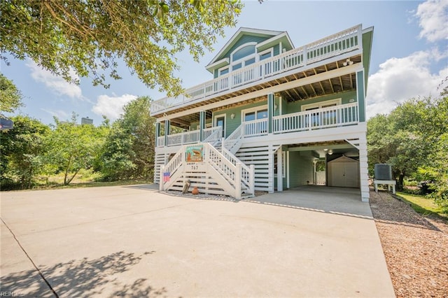 coastal home featuring covered porch, central AC, and a carport