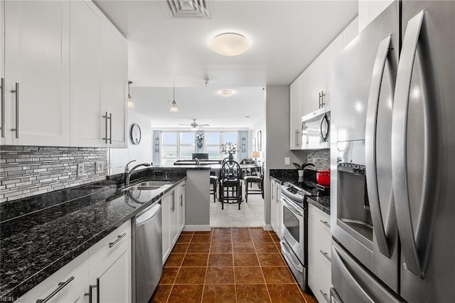 kitchen featuring white cabinets, tasteful backsplash, hanging light fixtures, dark stone countertops, and stainless steel appliances