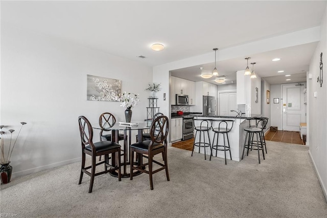 dining area featuring sink and light carpet