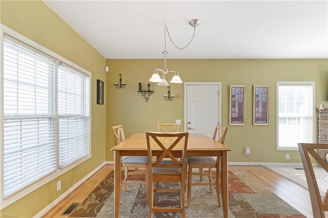 dining area with hardwood / wood-style flooring, a healthy amount of sunlight, and a chandelier