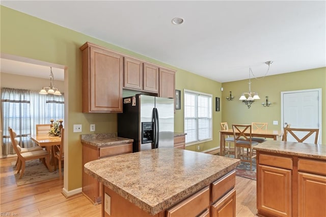 kitchen featuring a center island, light hardwood / wood-style floors, decorative light fixtures, a notable chandelier, and stainless steel fridge with ice dispenser