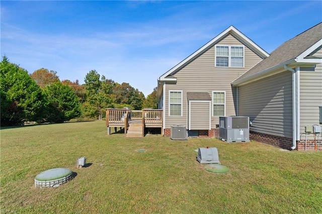 back of house with cooling unit, a wooden deck, and a lawn