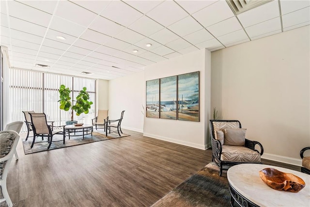 living area with a drop ceiling, dark hardwood / wood-style floors, and floor to ceiling windows