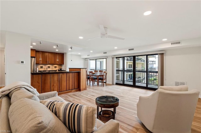 living room with light wood-type flooring and ceiling fan