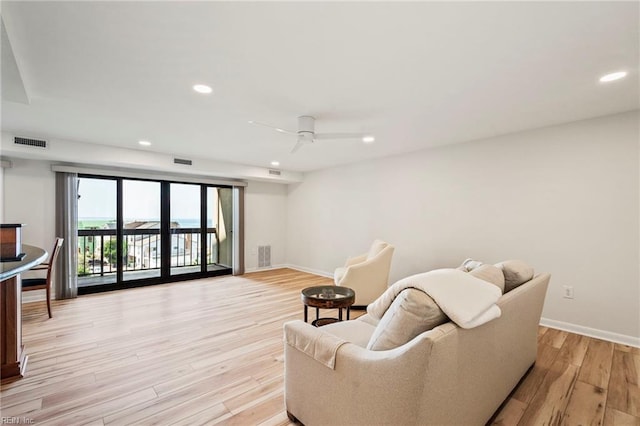 living room with light hardwood / wood-style flooring and ceiling fan