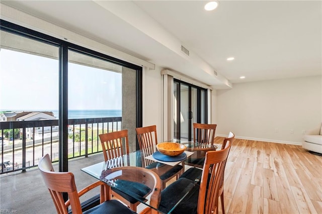 dining space featuring light hardwood / wood-style floors and a water view