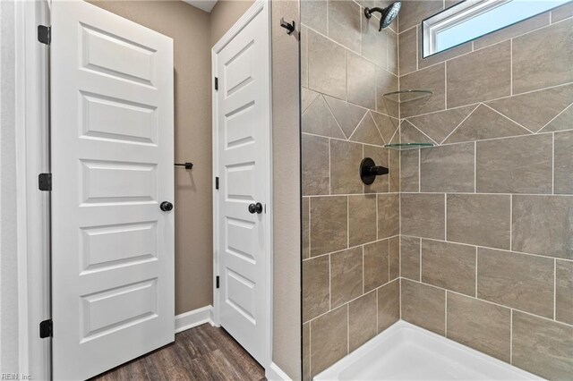 bathroom with a tile shower and hardwood / wood-style flooring