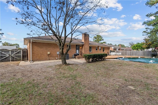 back of property featuring a fenced in pool, a patio, and a lawn