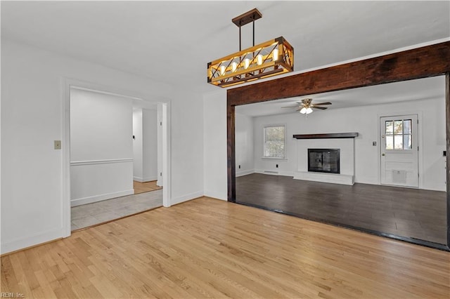 unfurnished living room with light hardwood / wood-style floors, a fireplace, and ceiling fan