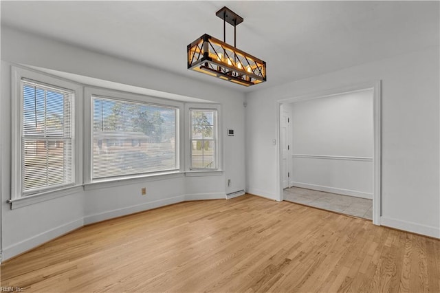 unfurnished dining area featuring a chandelier and light wood-type flooring