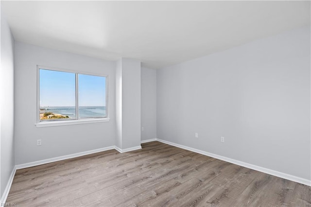 empty room with light hardwood / wood-style flooring and a water view