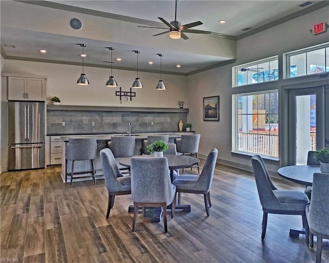 dining room with ornamental molding, dark wood-type flooring, a high ceiling, and ceiling fan