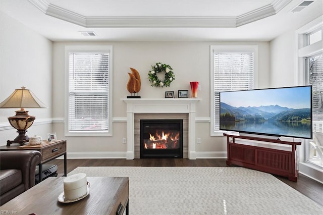 living room featuring ornamental molding, dark wood-type flooring, and a tray ceiling