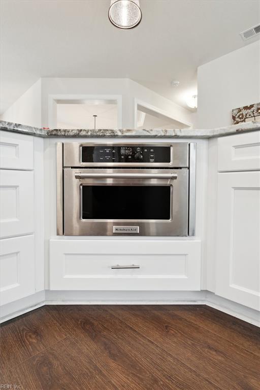 kitchen with dark hardwood / wood-style flooring, white cabinetry, and stainless steel oven