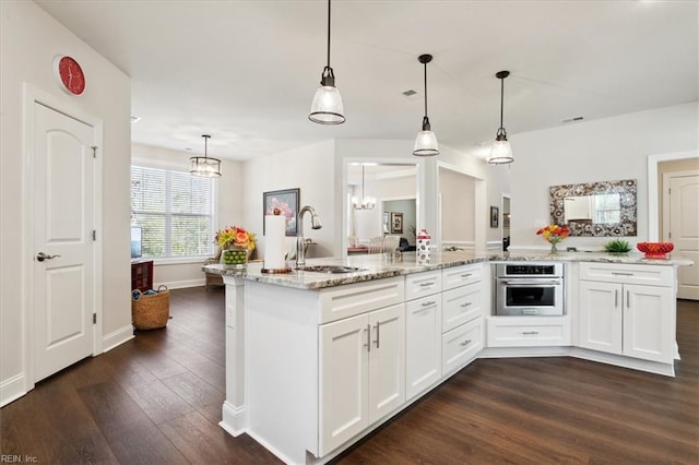 kitchen with oven, white cabinets, dark hardwood / wood-style flooring, pendant lighting, and sink