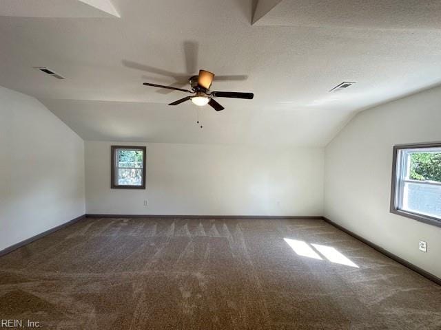 bonus room with lofted ceiling, a wealth of natural light, and dark colored carpet