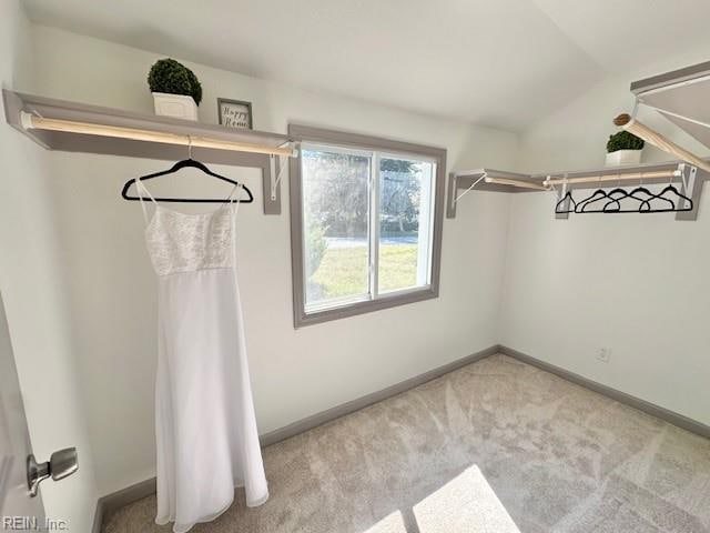 walk in closet with lofted ceiling and light colored carpet